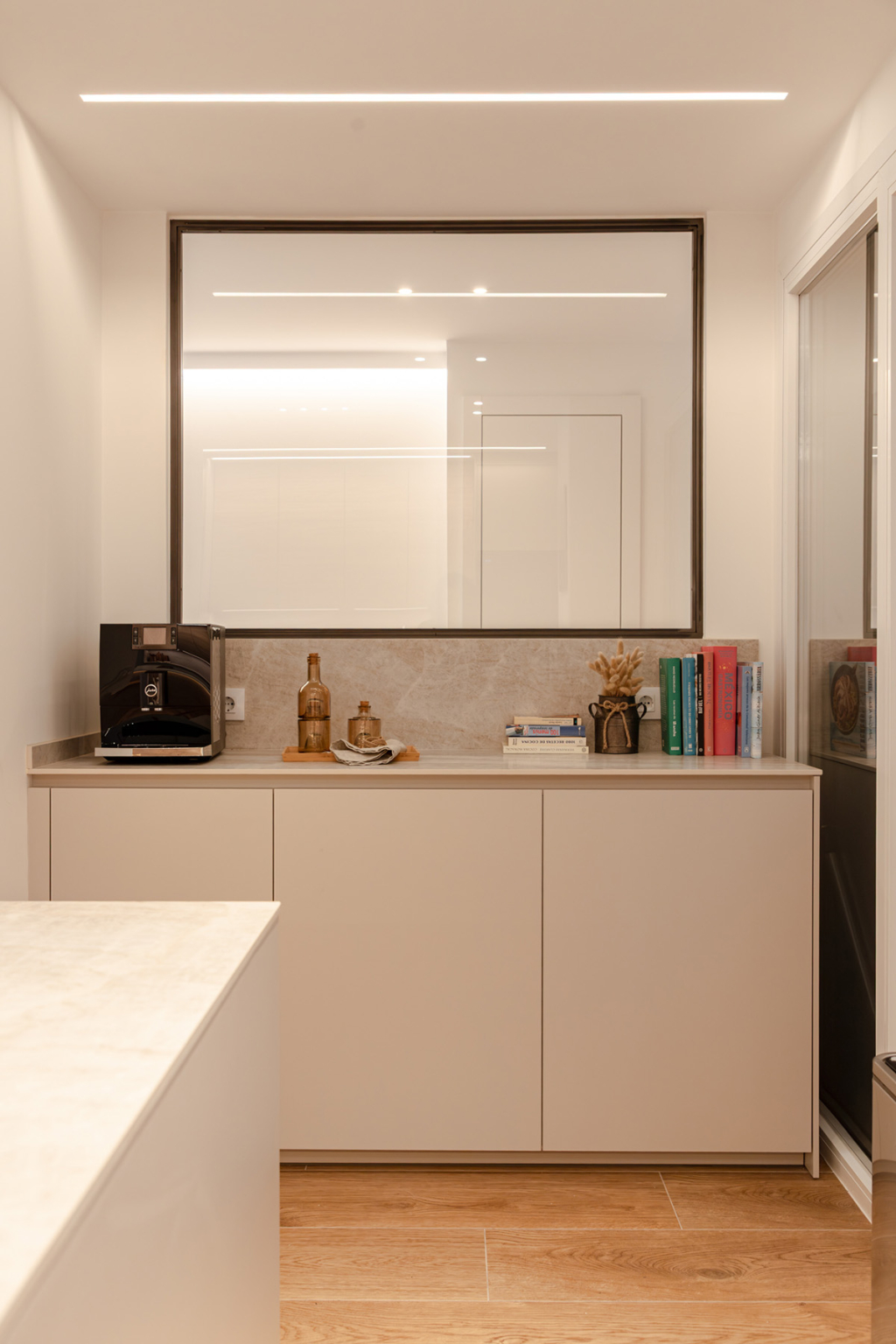 Aparador y espejo en una cocina Cashmere y madera diseñada por el estudio Santos Vaguada.