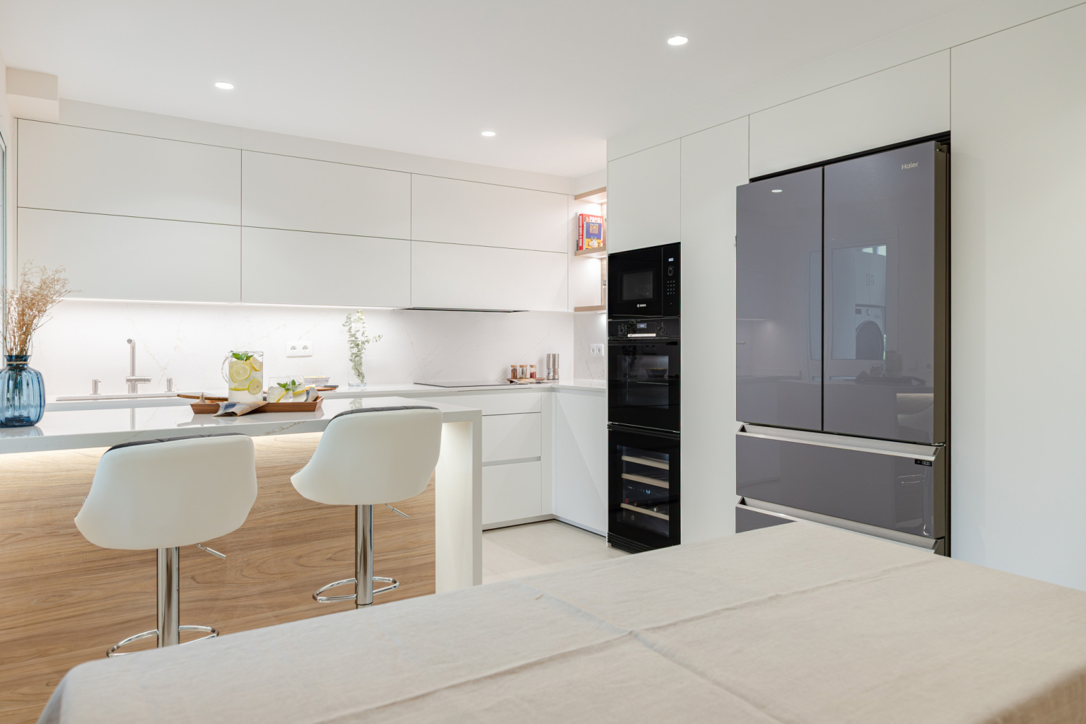 Cocina con office y península en bnalco y madera en un proyecto diseñado por Santos Vaguada.