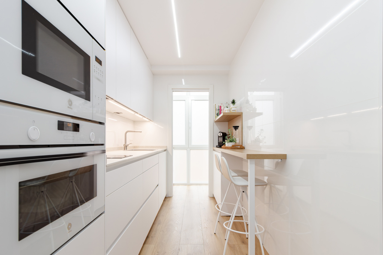 Cocina con office pequeña con barra de madera diseñada por el estudio de cocinas en Madrid Santos Vaguada.