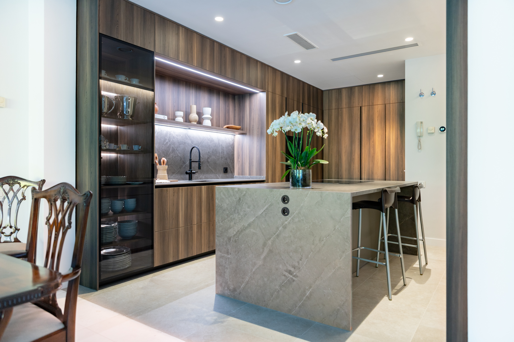 Cocina en Gris Visón y Laricio Fumé: isla central, vitrina Noir y zona de desayuno