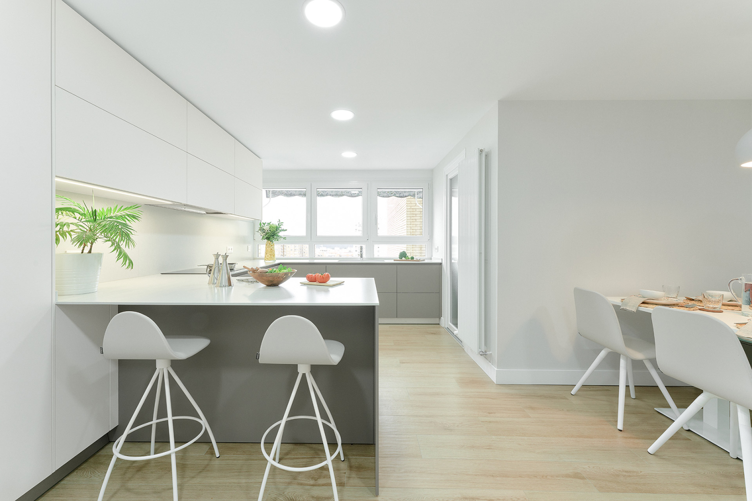 Cocina blanca con península abierta al comedor en un proyecto de la tienda de cocinas Santos Vaguada.
