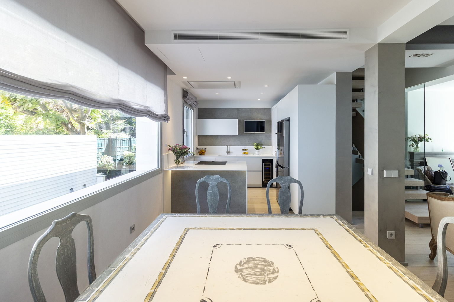 Cocina blanca y gris con península abierta al comedor diseñada por el estudio Santos Vaguada.